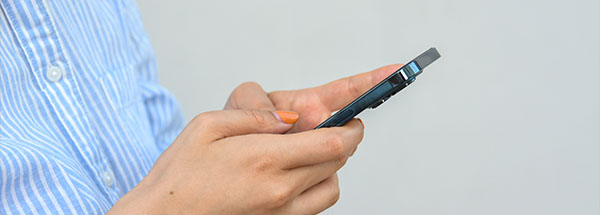 person holding a smartphone texting or using an app with a striped shirt and orange nail polish suitable for nine digital interactions